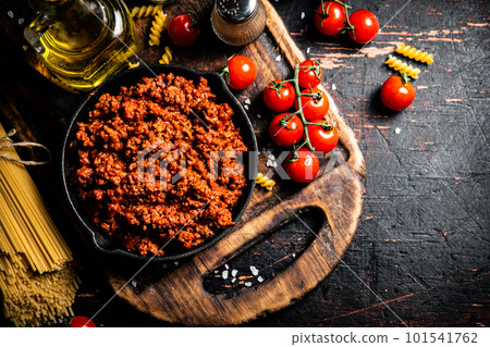 Bolognese sauce on a cutting board with cherry tomatoes and dry pasta. Bolognese sauce on a cutting board with cherry tomatoes and dry pasta. 101541762