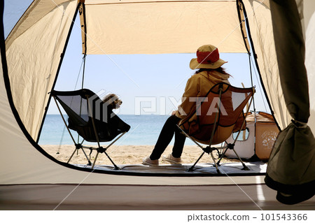 A girls' camp with a toy poodle Leisurely island camp on the blue sea and beautiful beach A woman enjoying camp food 101543366