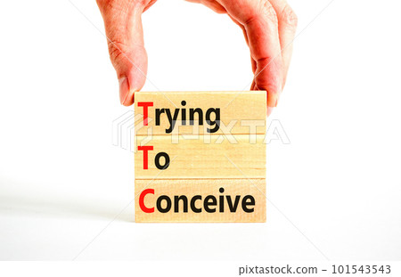 TTC trying to conceive symbol. Concept words TTC trying to conceive on wooden blocks on a beautiful white table white background. Businessman hand. Medical TTC trying to conceive concept. Copy space. 101543543
