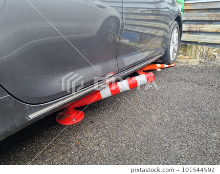 the car is parked with wheels on the barrier cones. the car is parked with wheels on the barrier cones. 101544592