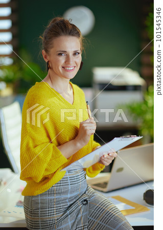 smiling trendy business owner woman in sweater in green office smiling trendy business owner woman in sweater in green office 101545346