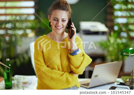 smiling business owner woman in green office talking on phone 101545347