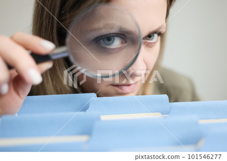 Woman looks through magnifier glass on folders with files Woman looks through magnifier glass on folders with files 101546277
