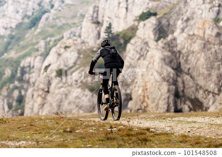 male cyclist riding mountain bicycle on mountainous region travelling cycling. backpack on back of mountain biker male cyclist riding mountain bicycle on mountainous region travelling cycling. backpack on back of mountain biker 101548508