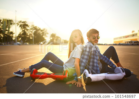Young man and woman riding on the Hoverboard in the park. content technologies. a new movement. Young man and woman riding on the Hoverboard in the park. content technologies. a new movement. 101548697
