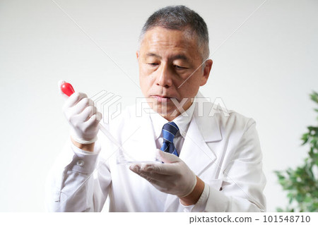 A male researcher wearing a white coat using laboratory equipment A male researcher wearing a white coat using laboratory equipment 101548710