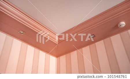 Part of the living room, corner of the wall from the ceiling, mounted LED lights in a wooden console on the ceiling, pink tinting 101548761