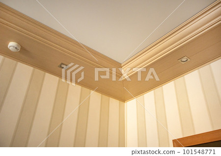 Part of the living room, corner of the wall from the ceiling, mounted LED lights in a wooden console on the ceiling 101548771