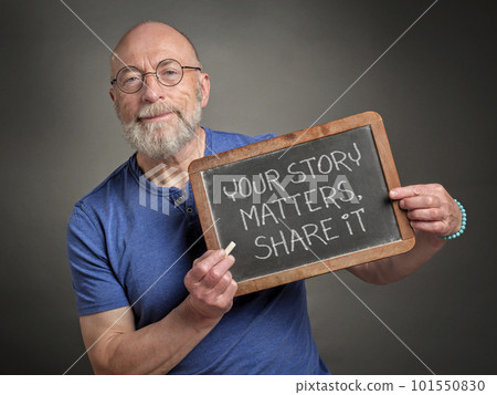 your story matters, share it - white chalk writing on a retro blackboard held by a senior man, presenter, teacher or mentor 101550830