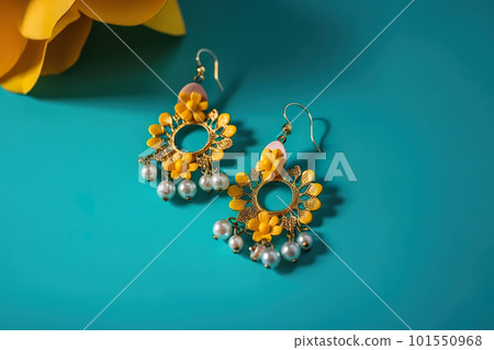 A pair of yellow and white earrings sitting on top of a blue surface. AI generative image 101550968