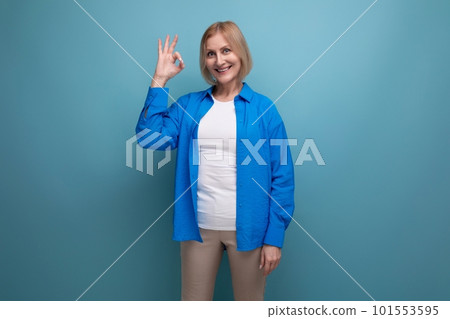 joyful smiling 50s middle aged woman in a blue shirt on a blue background with copy space joyful smiling 50s middle aged woman in a blue shirt on a blue background with copy space 101553595