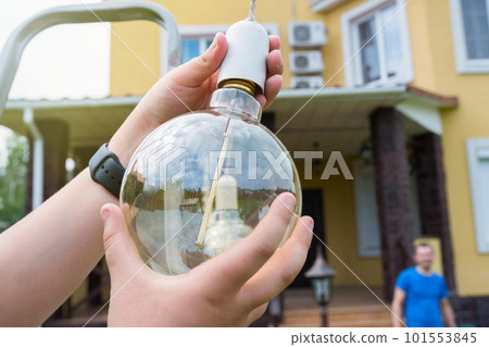 ncandescent lamp and children's hands close-up in the backyard on a sunny day 101553845