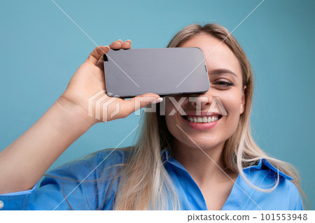 close-up of a european smiling blond girl holding a smartphone screen with a mockup for an close-up of a european smiling blond girl holding a smartphone screen with a mockup for an 101553948