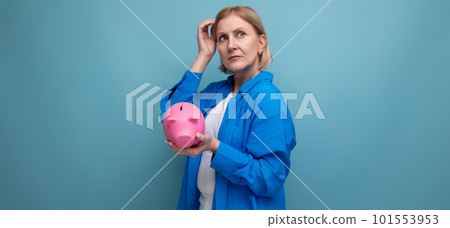 adult woman with a piggy bank of money on a blue background with copy space 101553953