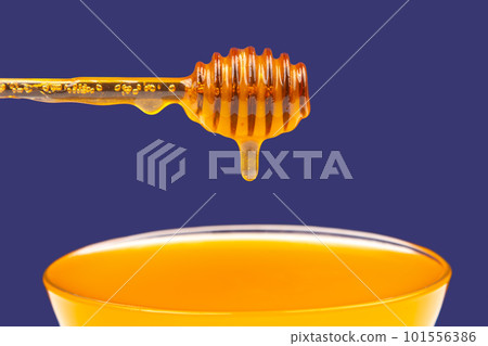 fresh fragrant honey dripping from a spoon into a plate on a blue background 101556386