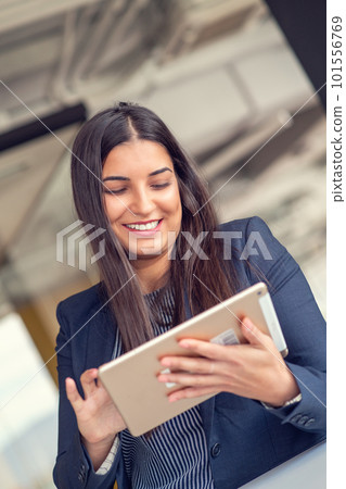 Young attractive female manager working on digital tablet while standing in modern office Young attractive female manager working on digital tablet while standing in modern office 101556769