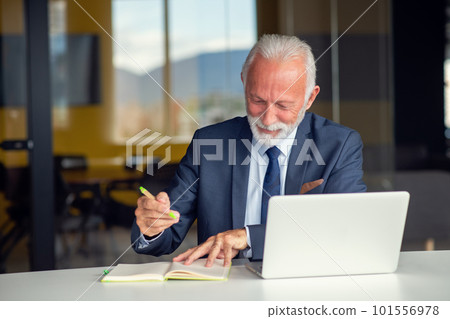 Handsome smiling senior man while sitting at his cozy workplace with laptop at home, retired male chatting with friends in social media, Handsome smiling senior man while sitting at his cozy workplace with laptop at home, retired male chatting with friends in social media, 101556978