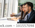 Creative business team sharing laptop in office, watching startup presentation, brainstorming, pointing at monitor, talking. 101557098