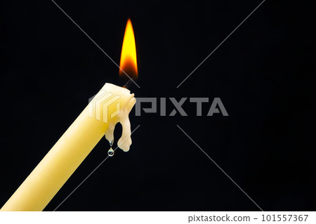 Lighting a candle with a wooden match on a dark background. Burning candle fire 101557367