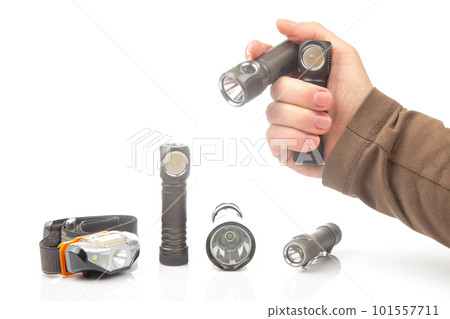 hand holds a flashlight against the background of other flashlights  101557711