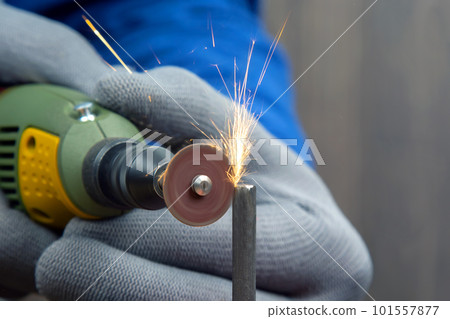 Worker processes metal with engraving drill close-up 101557877