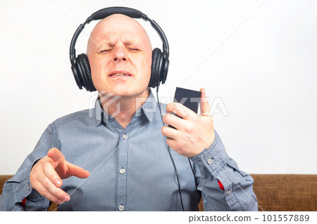 man with closed eyes listens to music with headphones on a light background man with closed eyes listens to music with headphones on a light background 101557889