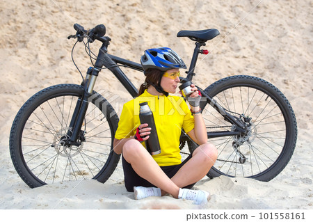 Beautiful woman cyclist in yellow with tea and thermos 101558161