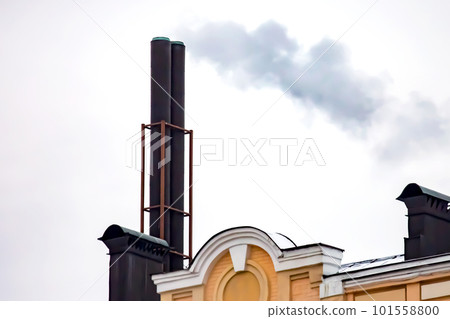 chimney with smoke coming out of the heating stove on the roof of the building 101558800