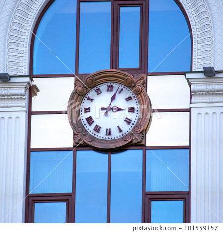 clock on the facade of a building with windows 101559157