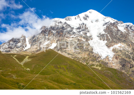 landscape of green grass and snowy mountains. Trekking and travel in Georgia 101562169