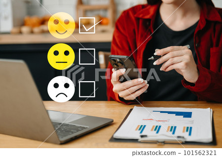 Customer service evaluation concept. woman Show face smile emoticon show on virtual screen from hand.looking at smart phone, tablet and laptop in office. 101562321