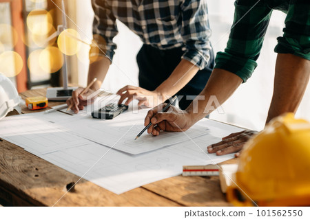 Two colleagues discussing data working and tablet, laptop with on on architectural project at construction site at desk in office 101562550