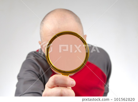 man hides his face with a magnifying glass. The concept of searching for a person in a database man hides his face with a magnifying glass. The concept of searching for a person in a database 101562820