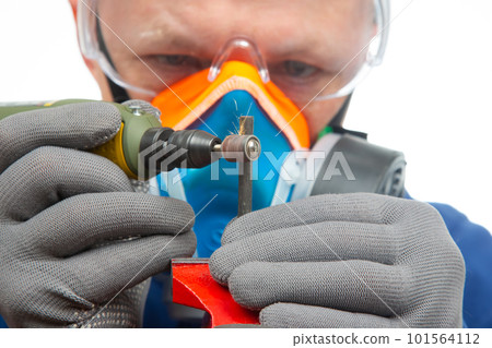 Male locksmith worker processes metal with engraving drill cutting.  101564112