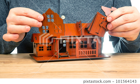 man assembles a model of a house with his hands 101564143