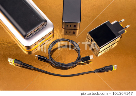 Power bank and charging plug with cable on a golden background. 101564147