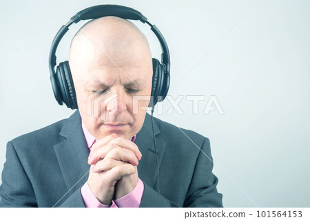 man with closed eyes listens to music with headphones on a light background man with closed eyes listens to music with headphones on a light background 101564153