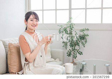 Japanese woman doing online shopping, reading, side job using smartphone on sofa at home Japanese woman doing online shopping, reading, side job using smartphone on sofa at home 101567299