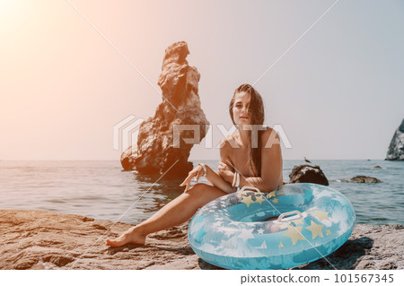 Woman summer sea. Happy woman swimming with inflatable donut on the beach in summer sunny day, surrounded by volcanic mountains. Summer vacation concept. Woman summer sea. Happy woman swimming with inflatable donut on the beach in summer sunny day, surrounded by volcanic mountains. Summer vacation concept. 101567345