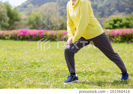 Senior woman stretching her legs in the park 101568418