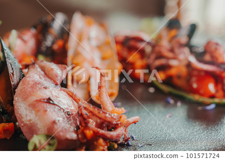 Grilled octopus with calmars, salad and lemon on plate. Close up view. 101571724