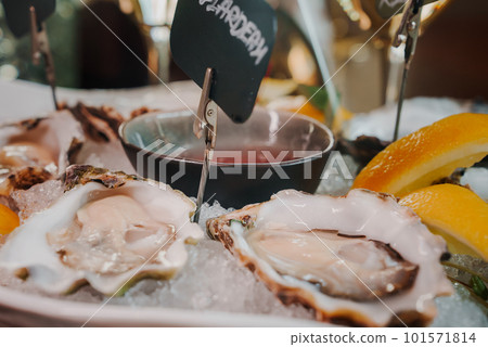 Fresh Oysters close up on a plate, served table with oysters, lemon and ice. Healthy sea food. Fresh Oyster dinner with sparkling wine in a restaurant. Gourmet food 101571814