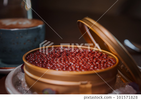 Black caviar in can placed on a plate with ice. A chocolate dessert styled as a caviar Black caviar in can placed on a plate with ice. A chocolate dessert styled as a caviar 101571828