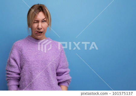 charming blond young millennial woman in casual look makes a grimace on a bright background with 101575137