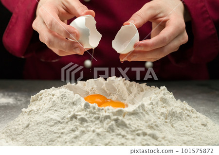Adding egg to a pile of flour Adding egg to a pile of flour 101575872