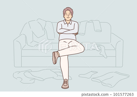 Bachelor man sits on couch among scattered clothes and is too lazy to start cleaning Bachelor man sits on couch among scattered clothes and is too lazy to start cleaning 101577263