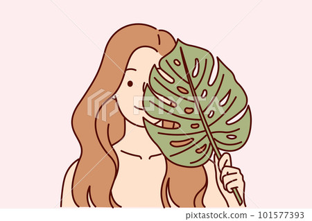 Beautiful woman applies leaf from palm tree to face, symbolizing natural cosmetic product for skin Beautiful woman applies leaf from palm tree to face, symbolizing natural cosmetic product for skin 101577393