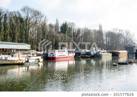 A long, narrow boat moored on the River Thames outside London 101577626