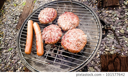 Hamburgers and frankfurters being grilled on the barbecue stove Hamburgers and frankfurters being grilled on the barbecue stove 101577642
