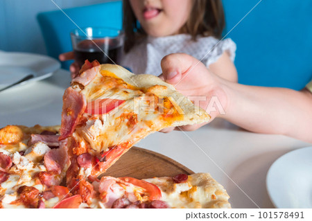 Hand with a slice of pizza on the table, close up Hand with a slice of pizza on the table, close up 101578491